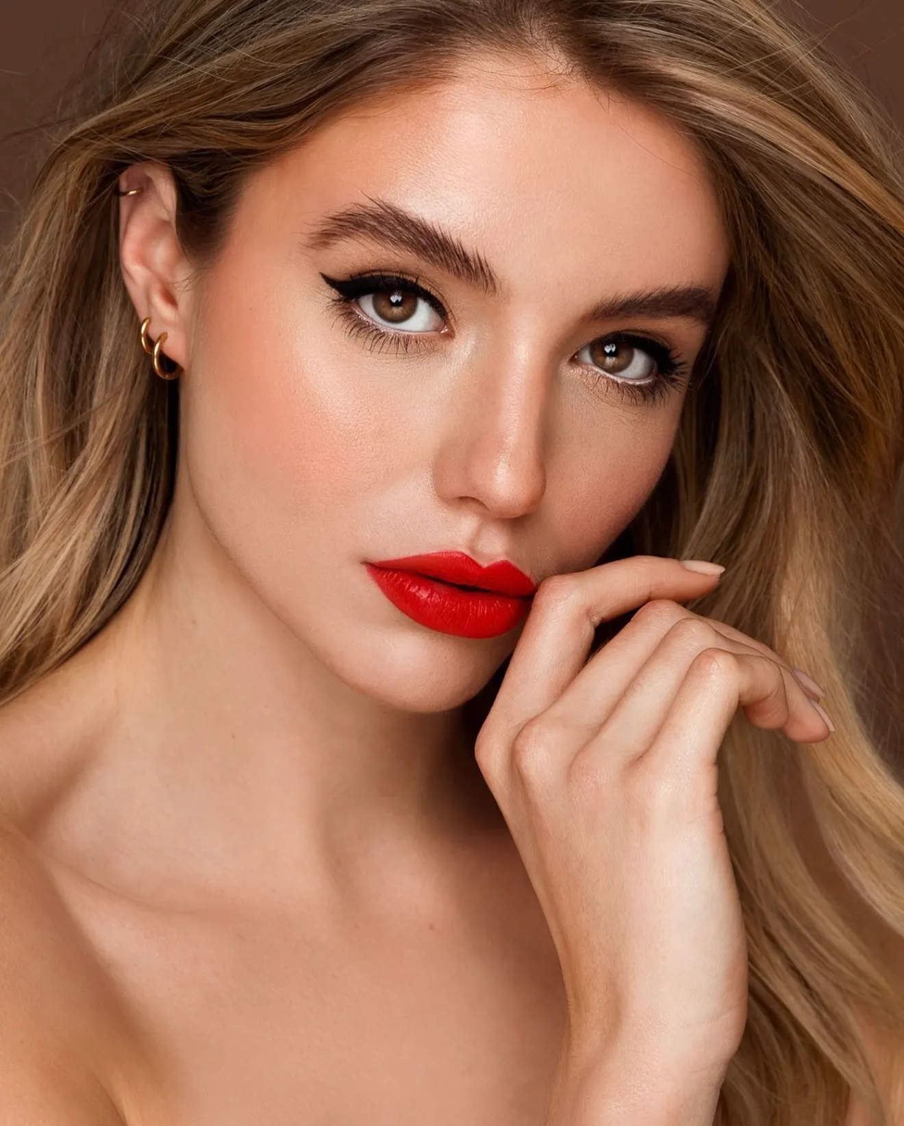 Model met rode lippen en eyeliner, vinger bij de mond